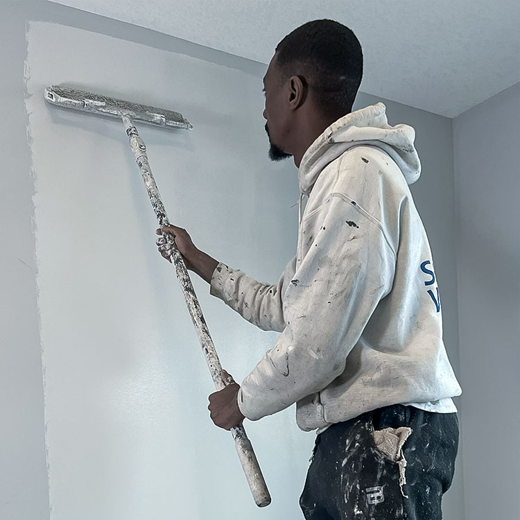Muz using paint roller on white wall