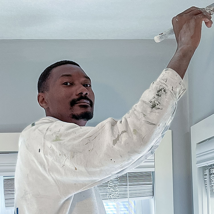 Muz using paintbrush on white wall